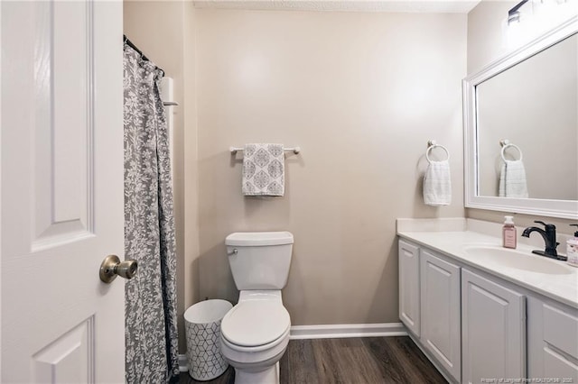 bathroom with vanity, toilet, wood finished floors, and baseboards