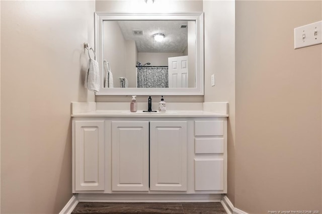 full bath featuring visible vents, baseboards, a textured ceiling, and vanity