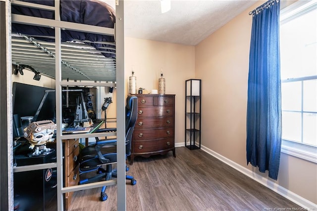 bedroom with a textured ceiling, baseboards, and wood finished floors