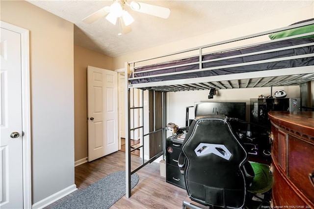 bedroom with a textured ceiling, a ceiling fan, baseboards, and wood finished floors