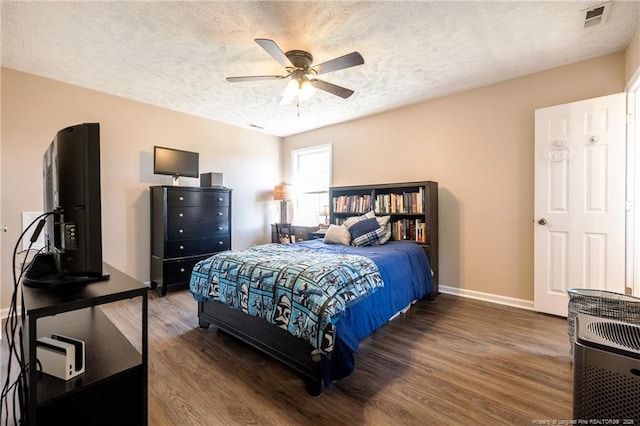 bedroom featuring visible vents, baseboards, wood finished floors, a textured ceiling, and a ceiling fan