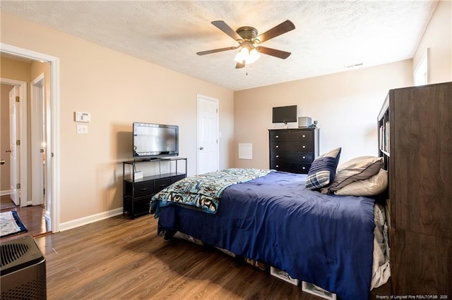 bedroom with visible vents, a ceiling fan, a textured ceiling, wood finished floors, and baseboards