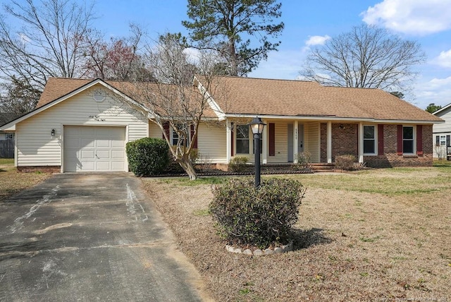 ranch-style home featuring aphalt driveway, an attached garage, brick siding, and a front yard