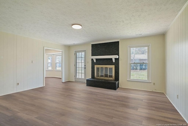 unfurnished living room with a healthy amount of sunlight, wood finished floors, and a fireplace