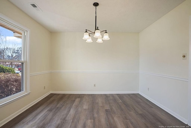 unfurnished room with a chandelier, visible vents, baseboards, and dark wood-style floors