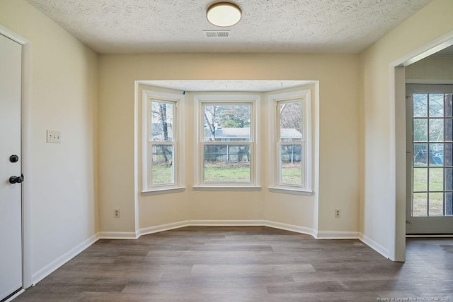 unfurnished dining area with plenty of natural light, dark wood-style floors, and visible vents