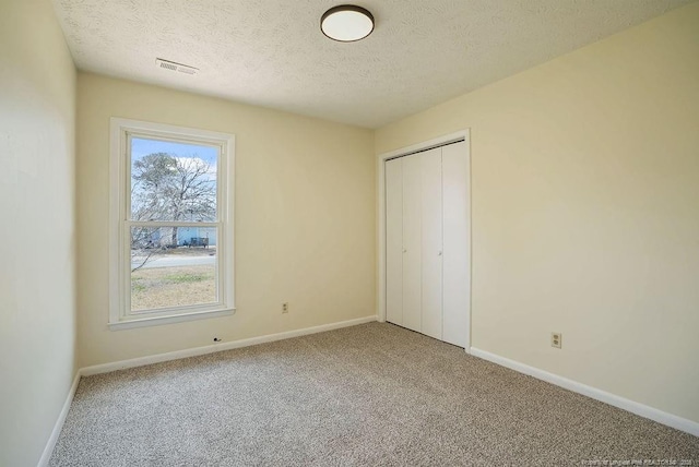 unfurnished bedroom with a closet, visible vents, carpet flooring, and baseboards