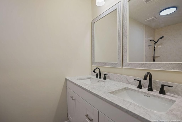 bathroom featuring double vanity, visible vents, a shower, and a sink