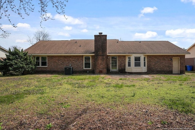 back of house with cooling unit, a shingled roof, a chimney, a lawn, and brick siding