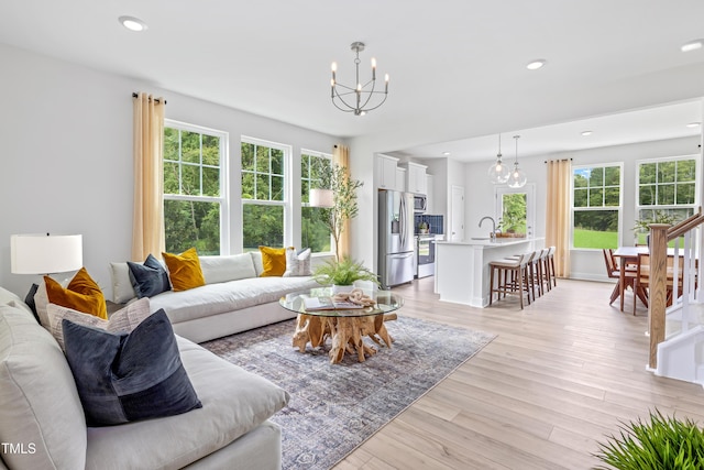 living room featuring an inviting chandelier, recessed lighting, light wood-type flooring, and a wealth of natural light