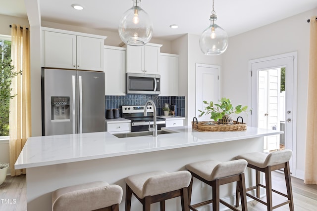 kitchen featuring decorative backsplash, a healthy amount of sunlight, light wood-style floors, and stainless steel appliances