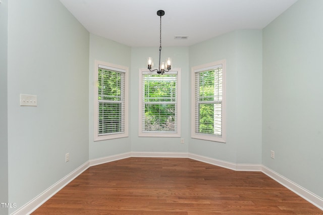 unfurnished room featuring dark wood finished floors, a chandelier, and visible vents