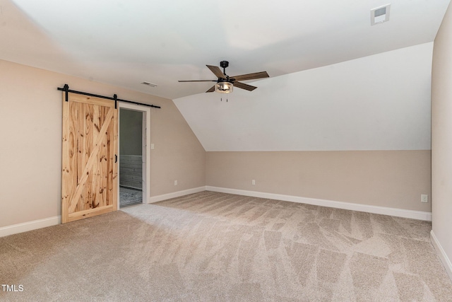 additional living space with baseboards, ceiling fan, carpet, and a barn door