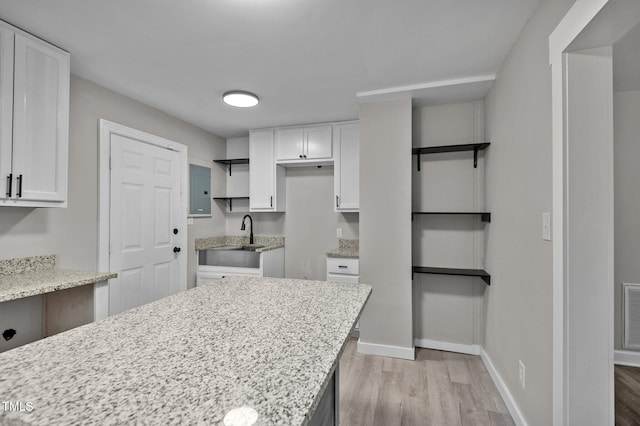 kitchen featuring light stone counters, white cabinetry, and light wood-style floors