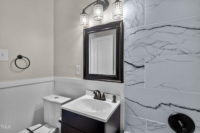 half bath featuring vanity and a wainscoted wall