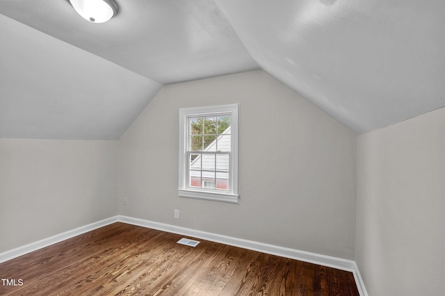 additional living space with visible vents, lofted ceiling, baseboards, and wood finished floors