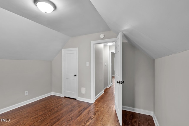 bonus room with baseboards, lofted ceiling, and dark wood finished floors