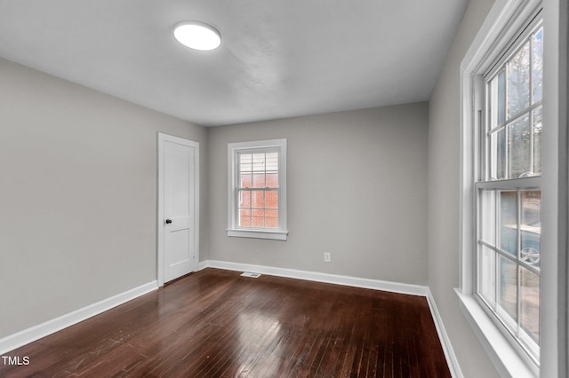 unfurnished room featuring visible vents, dark wood-type flooring, and baseboards