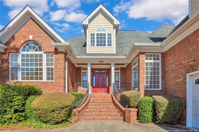 entrance to property featuring brick siding and roof with shingles