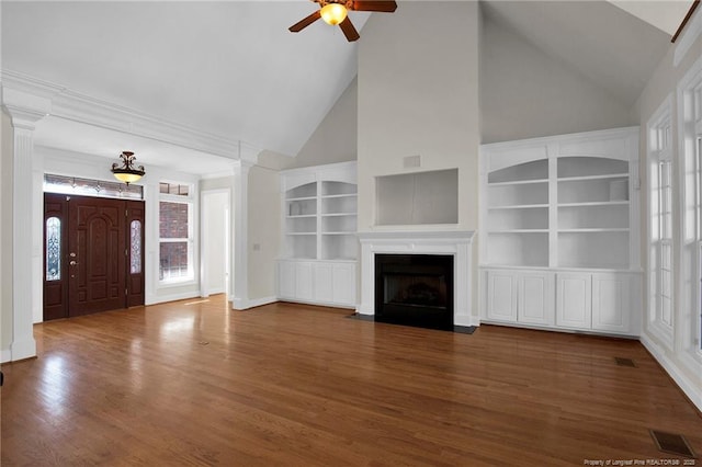 unfurnished living room with visible vents, ceiling fan, a fireplace with flush hearth, decorative columns, and wood finished floors