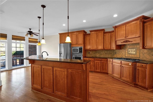 kitchen featuring a ceiling fan, dark countertops, appliances with stainless steel finishes, and brown cabinetry