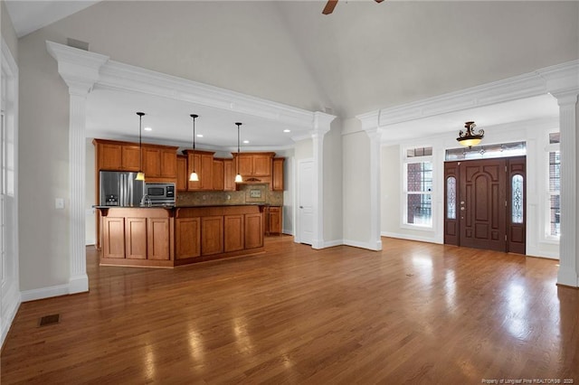 kitchen with visible vents, decorative columns, decorative backsplash, appliances with stainless steel finishes, and brown cabinets