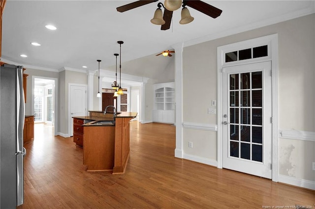 kitchen featuring ornamental molding, a sink, wood finished floors, freestanding refrigerator, and ceiling fan