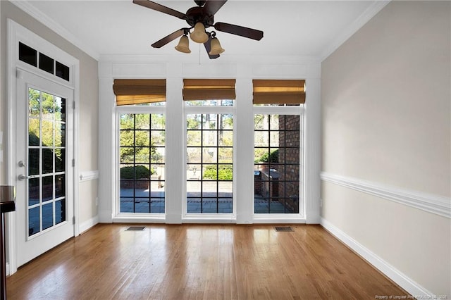 interior space with crown molding, wood finished floors, visible vents, and ceiling fan