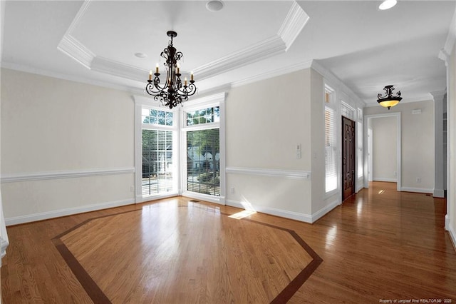 unfurnished dining area with a tray ceiling, wood finished floors, baseboards, and a chandelier