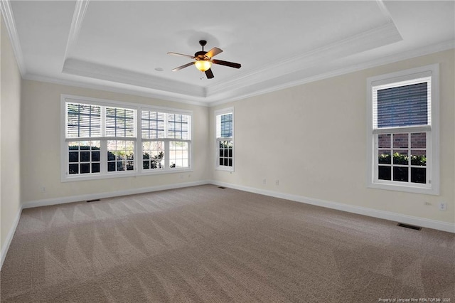 carpeted spare room with visible vents, a ceiling fan, baseboards, crown molding, and a raised ceiling