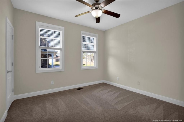 carpeted spare room featuring visible vents, baseboards, and ceiling fan