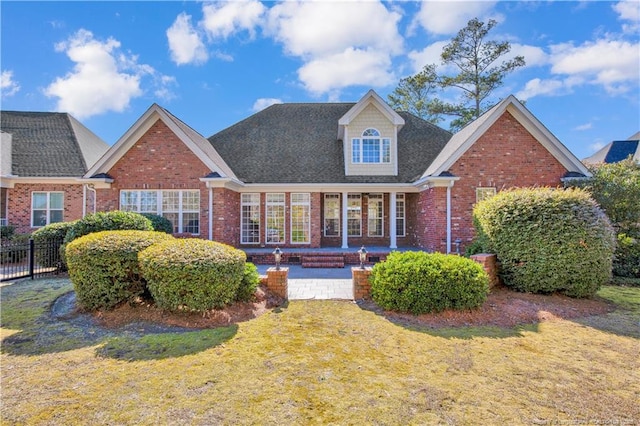 rear view of house with a yard, brick siding, and fence