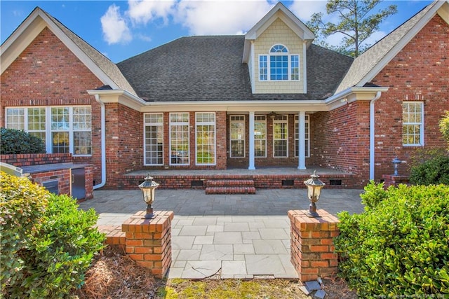 back of property with brick siding, a porch, and a shingled roof