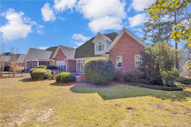 view of front of property with brick siding, a front yard, and fence