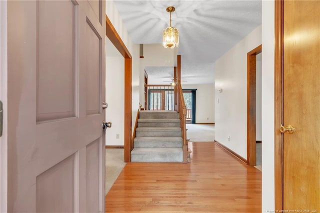 entrance foyer featuring light carpet, stairway, light wood-type flooring, and baseboards