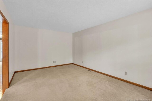 unfurnished room featuring visible vents, light colored carpet, and baseboards