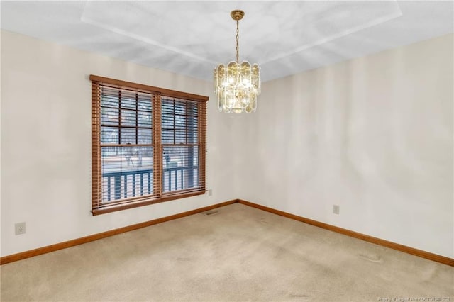 empty room featuring visible vents, baseboards, a chandelier, and carpet flooring