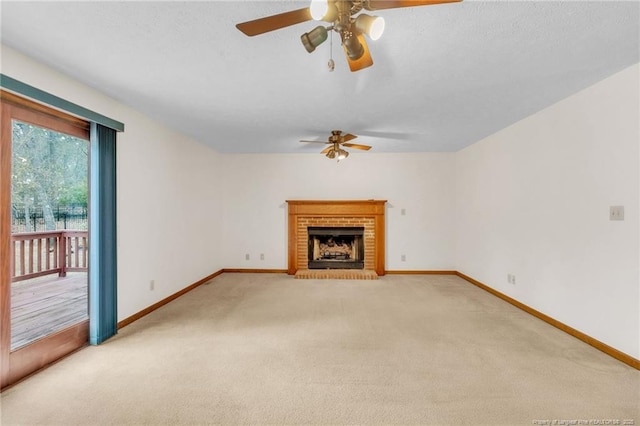 unfurnished living room with baseboards, light colored carpet, a brick fireplace, and a ceiling fan