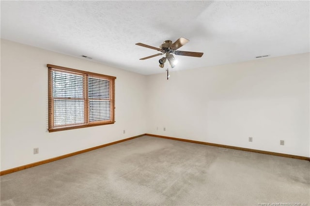 spare room with visible vents, light carpet, a textured ceiling, and a ceiling fan