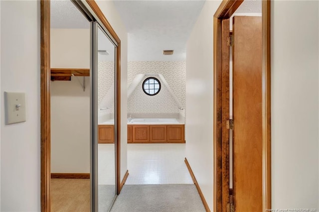 hall featuring wallpapered walls and baseboards