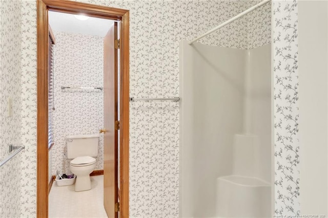 bathroom with wallpapered walls, toilet, and a shower