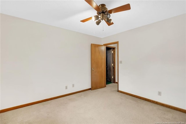 spare room featuring a ceiling fan, baseboards, and light carpet