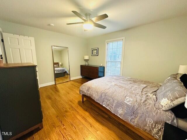 bedroom featuring baseboards, wood finished floors, and a ceiling fan