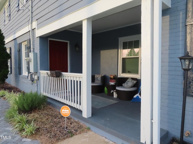 view of exterior entry featuring brick siding and covered porch