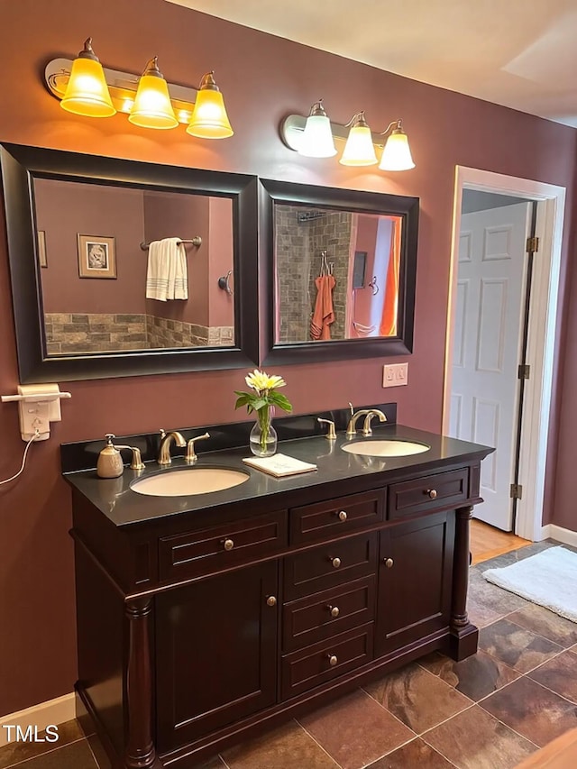 full bath with double vanity, a sink, and baseboards