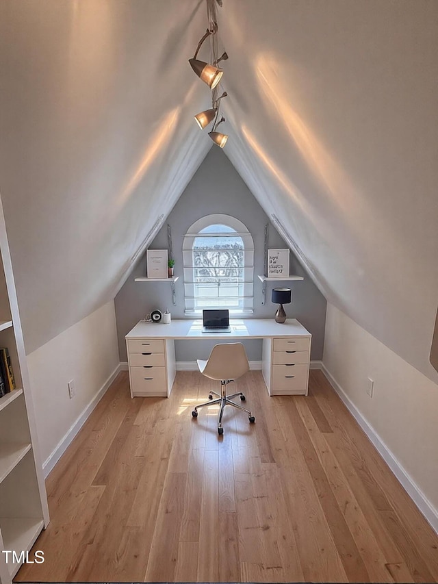 unfurnished office with light wood finished floors, baseboards, lofted ceiling, and rail lighting