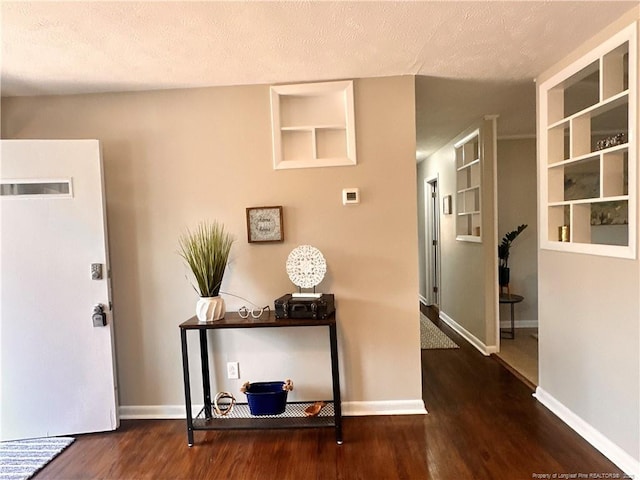 foyer with wood finished floors, baseboards, and a textured ceiling