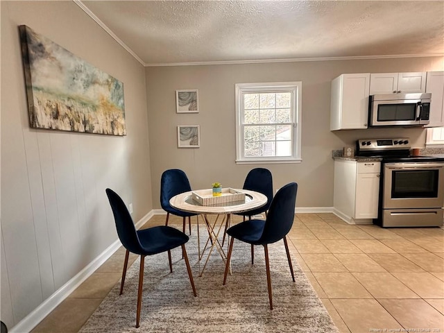 dining room featuring light tile patterned floors, baseboards, a textured ceiling, and ornamental molding