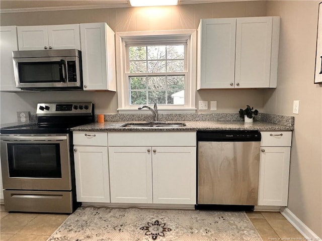 kitchen with light tile patterned floors, stone counters, stainless steel appliances, white cabinetry, and a sink