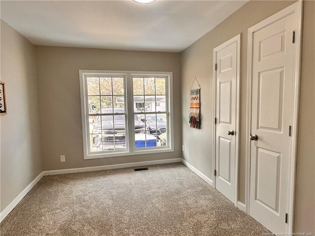 carpeted spare room featuring visible vents and baseboards